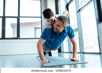 happy father doing push up exercise with son on back at gym with copy space - Powered by Shutterstock