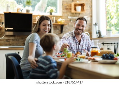 Happy father feeding her small boy while having breakfast in the kitchen - Powered by Shutterstock