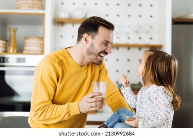 Happy father giving his small daughter a glass of milk during breakfast time. Focus is on little girl - Powered by Shutterstock