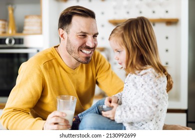 Happy father giving his small daughter a glass of milk during breakfast time - Powered by Shutterstock