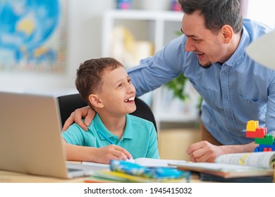 Happy Father Helps His Son With His Homework Using A Laptop During Distance Learning. A Parent Explains A New Topic To A Child In An Online Lesson. Achieving Excellence Together And Enjoying Success