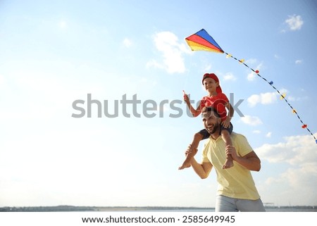 Happy father and his child playing with kite on sunny day. Spending time in nature