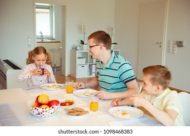 Happy father with his cute children talking at the breakfast at home