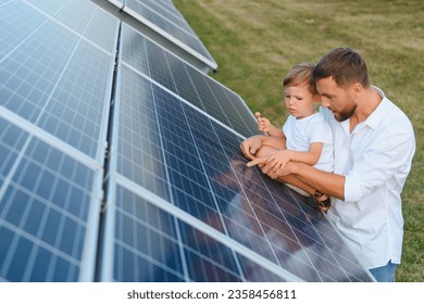 Happy father and his little son are walking near the solar panels. The concept of green energy - Powered by Shutterstock