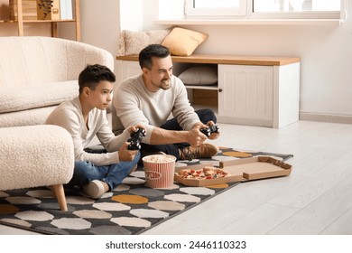 Happy father and his little son with tasty food playing video games at home - Powered by Shutterstock