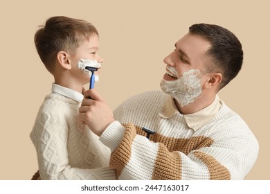 Happy father and his little son shaving on beige background - Powered by Shutterstock