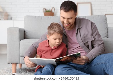 Happy father and his little son reading book together at home - Powered by Shutterstock