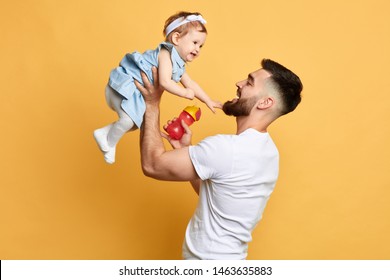 Happy Father Holding His Little Kid In Hands Isolated Over Yellow Background, Family, Love,warm Relationship. Close Up Side View Photo.feeling And Emotion