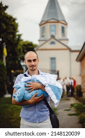 Happy father holding his little son in his arms. The father carries the child to the church to be baptized.