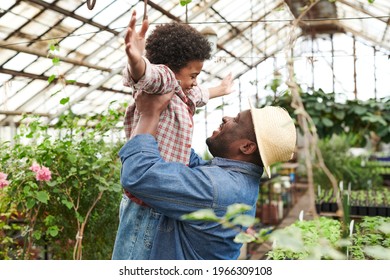 Happy father holding his son they having fun during their work in the greenhouse - Powered by Shutterstock