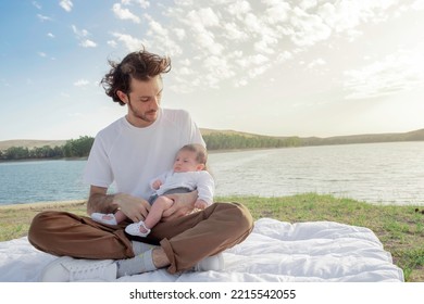 Happy Father Holds His Daughter In His Arms On A Beautiful Sunny Day Outdoors At The Lake. Little Girl Rests In Her Father's Arms. Beautiful Single Parent Father-daughter Family Portrait. Cloud Sunset