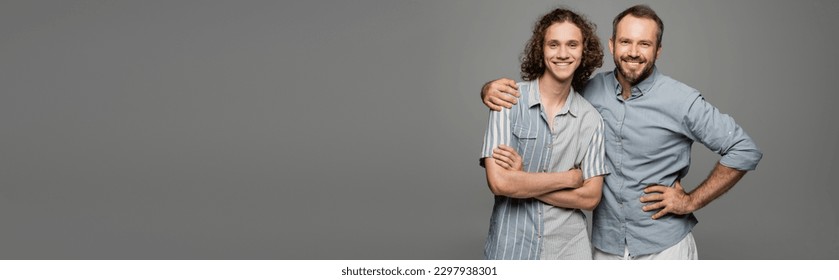 happy father hugging shoulder of positive teenage son isolated on grey, banner - Powered by Shutterstock