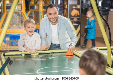 Happy Father With Kids Playing Air Hockey In Entertainment Center