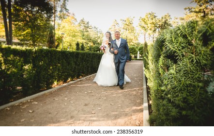 Happy father leads beautiful bride to the altar at park - Powered by Shutterstock