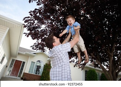 Happy Father Lifting His Cute Son In The Air