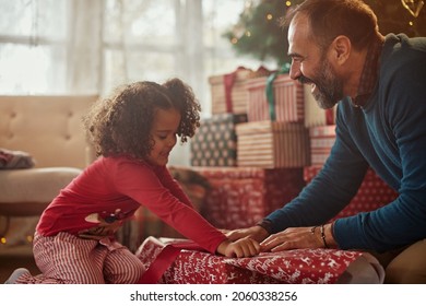 Happy father and mixed race daughter opening Christmas gifts together and smiling. Holidays concepts - Powered by Shutterstock