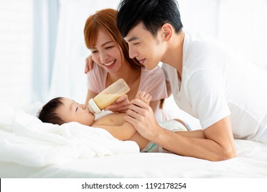 happy father and mother feeding baby from bottle