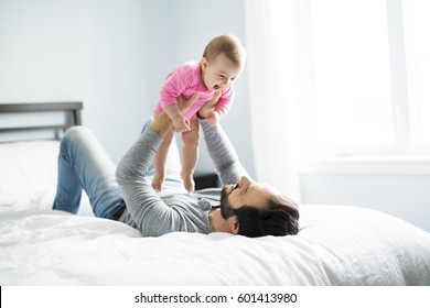 A happy father playing with adorable baby in bedroom - Powered by Shutterstock