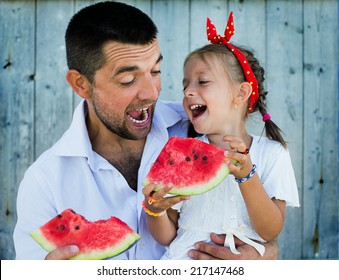 happy father playing with cute little daughter holding  watermelon
