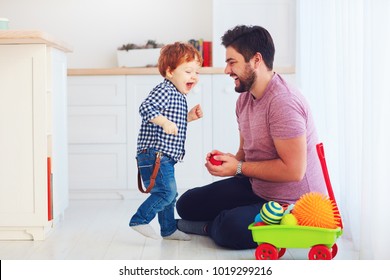 happy father playing with cute toddler baby son at home, family games