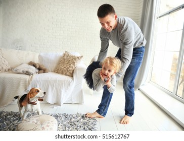 Happy Father Playing With His Baby Daughter In The Bright Living Room Near The Window . The Concept Of Friendly Family.