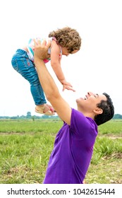 Happy Father Playing With His Daughter Outside. Dad Holding Baby Girl Toddler Up In The Air At Outdoor. Fatherhood Concept