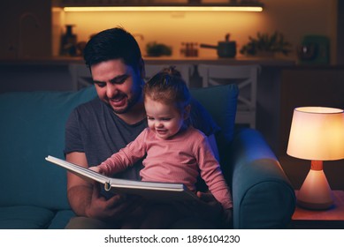 Happy Father Is Reading A Fairytale Book To Toddler Baby Girl At Home. Bedtime Story