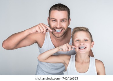 happy father and son brushing teeth and looking at camera together isolated on grey - Powered by Shutterstock