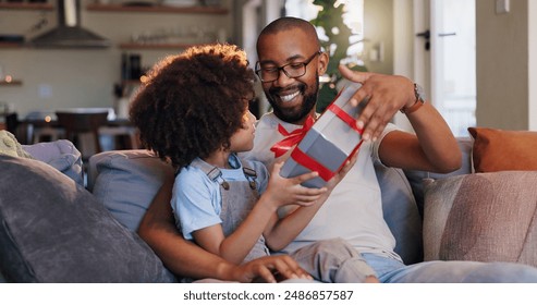 Happy father, son and gift with box for birthday surprise, childhood or bonding on sofa at home. Dad giving child, kid or little boy present, parcel or package with ribbon for appreciation at house - Powered by Shutterstock