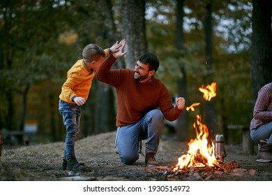Fröhlicher Vater mit Sohn, der fünf in der Nähe des Lagerfeuers gibt