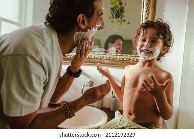 Happy father and son having fun with shaving cream in the bathroom. Father and son smiling cheerfully with shaving foam on their faces. Loving father bonding with his young son at home. - Powered by Shutterstock