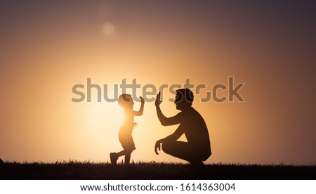Happy father and son moment. Father giving his son a hight five outdoors in the park. Father's Day, fatherhood concept. 
