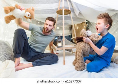 Happy Father And Son Sitting In Blanket Fort And Playing With Teddy Bears 