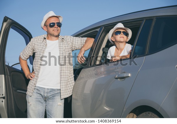Happy father and son sitting in the car\
at the day time. They look out the window. People having fun\
outdoors. Concept of the family is ready for\
travel.