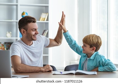 The happy father and a son sitting at the desk and gesturing - Powered by Shutterstock