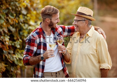 Happy father and son tasting wine in vineyard
