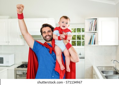 Happy father in superhero costume lifting son in kitchen - Powered by Shutterstock