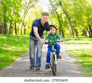 Happy father teaching young son to ride a bike