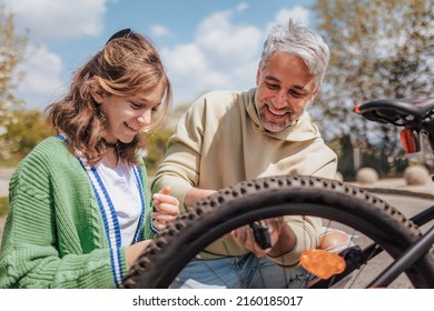 Happy father with teenage daughter repairing bicycle in street in town. - Powered by Shutterstock