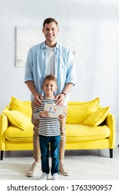 Happy Father Touching Shoulders Of Son Holding Handmade Fathers Day Greeting Card With Lettering And Heart Symbol