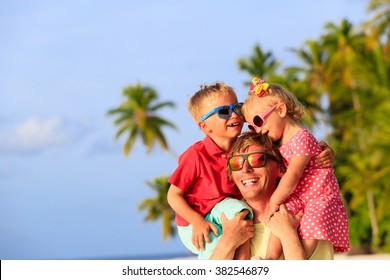 Happy Father With Two Kids On Shoulders Having Fun At Beach