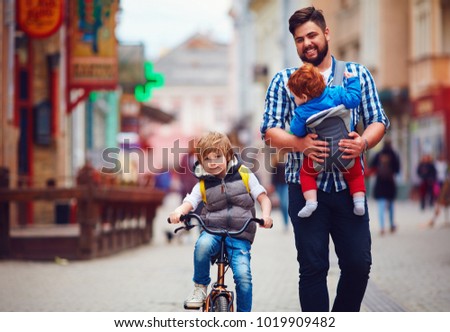 happy father and two sons on the city walk. Parental leave. Baby carrier
