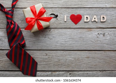 Happy Fathers Day Card With Male Presents, Love Dad Letters, Present And Red And Black Striped Necktie On Rustic Wood Background, Copy Space, Top View