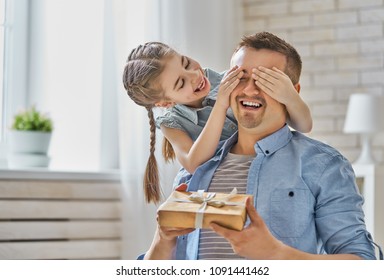 Happy father's day! Child daughter congratulating dad and giving him gift box. Daddy and girl smiling and hugging. Family holiday and togetherness.