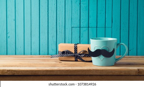 Happy Fathers day concept with coffee cup, mustache and gift box over wooden background