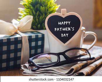 Happy fathers day concept. coffee cup with gift box, heart tag with Happy father's day text and newspaper, glasses on wooden table background. - Powered by Shutterstock