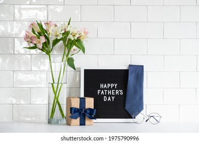 Happy Fathers day concept. Festive composition with gift box wrapped craft paper with blue ribbon, letterboard with text Happy Father's Day, necktie, boquet of flowers, glasses. - Powered by Shutterstock