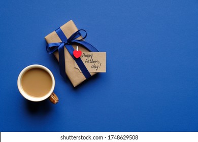 Happy Father's Day Concept. Flat Lay Composition With Vintage Gift Box Wrapped Blue Ribbon And Cup Of Coffee On Blue Background. Fathers Day Card Template, Banner Mockup.