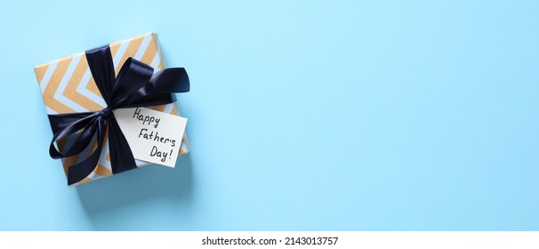 Happy Fathers day concept. Flat lay vintage gift box with blue ribbon bow and label Happy Father's day on color background. Fathers day wide banner design. - Shutterstock ID 2143013757