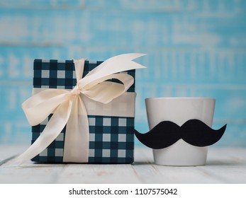 Happy father's day concept. gift box, a cup of coffee with mustache on white and blue background. - Powered by Shutterstock